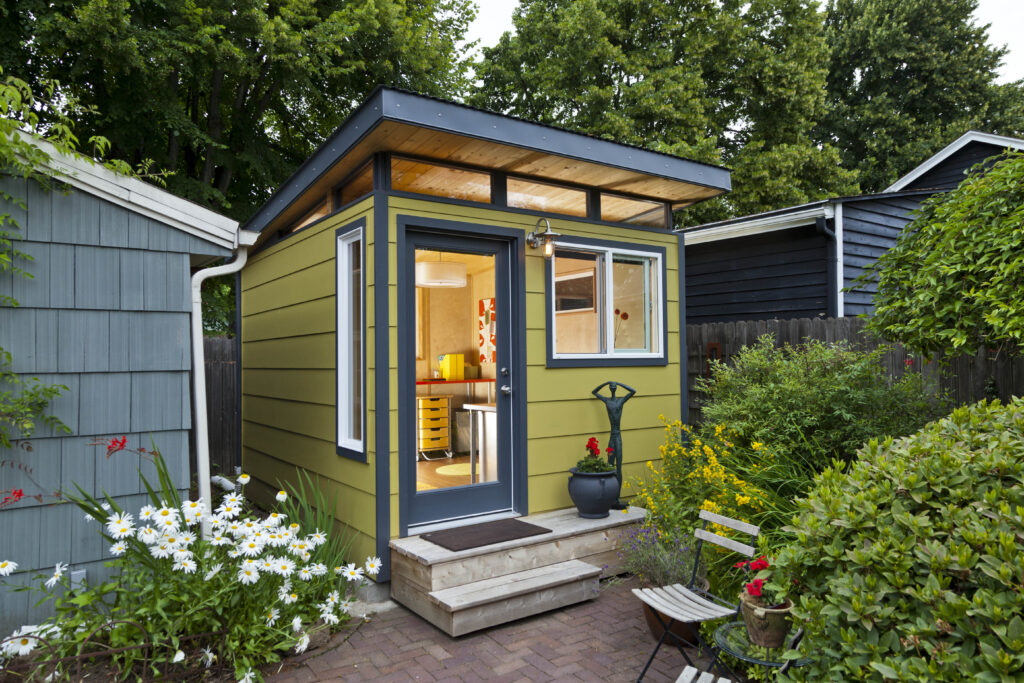 Green backyard shed with garden landscaping and patio
