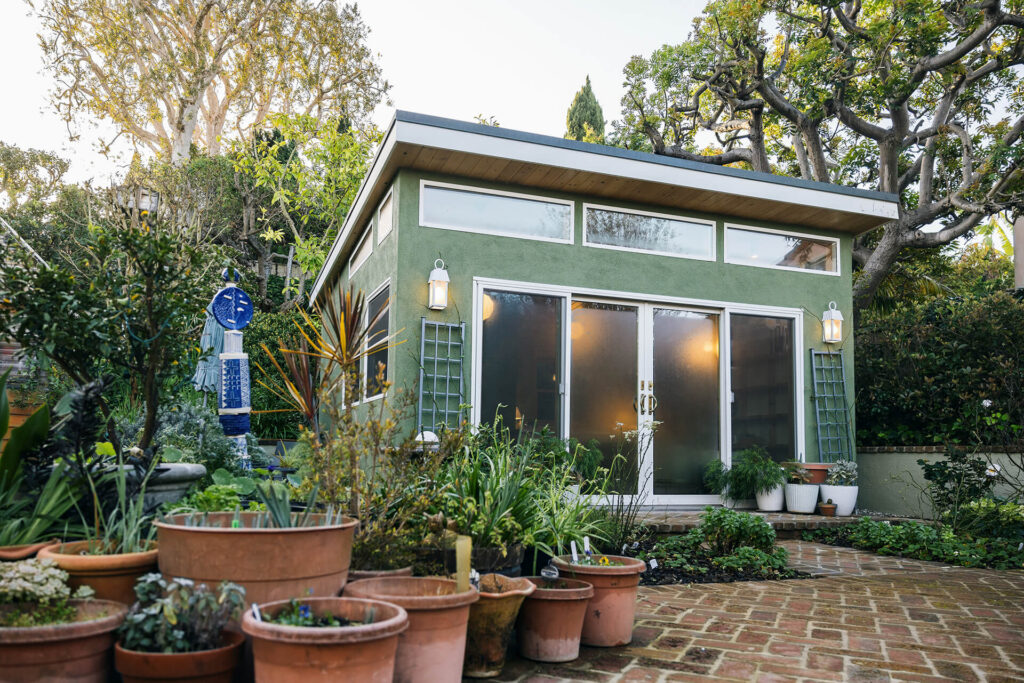 Green backyard studio shed with sliding glass doors
