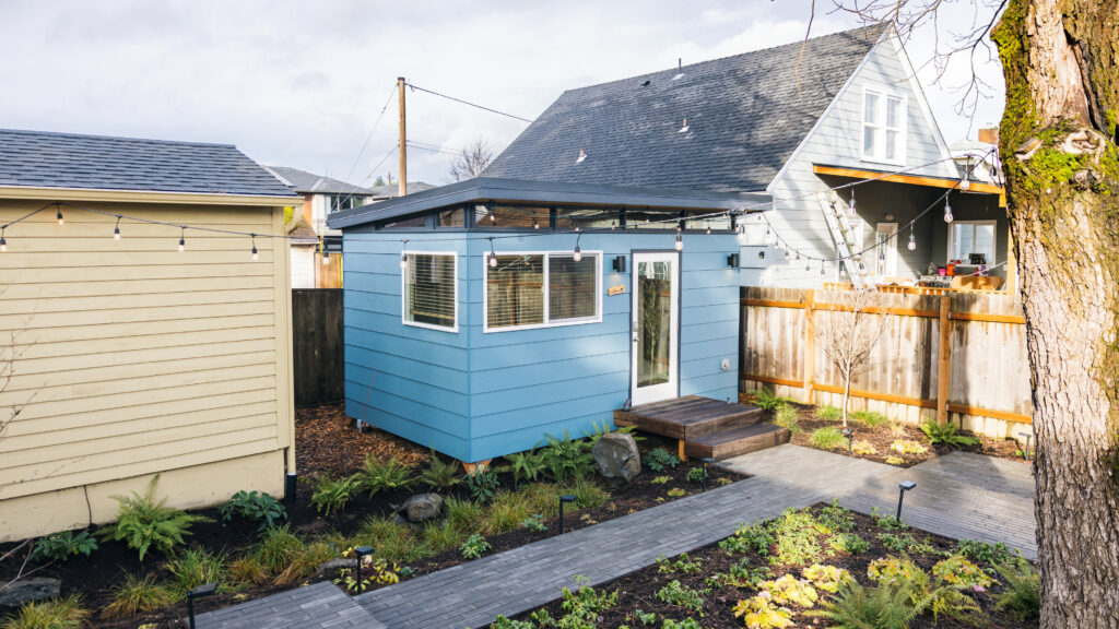 Blue backyard shed with pathway and garden landscaping