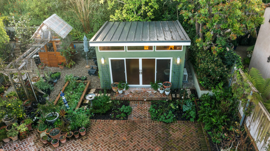 Green backyard studio shed with brick patio and garden