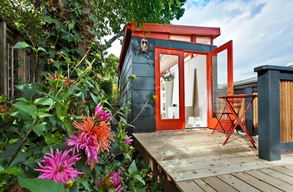 Small black shed with red doors and outdoor deck
