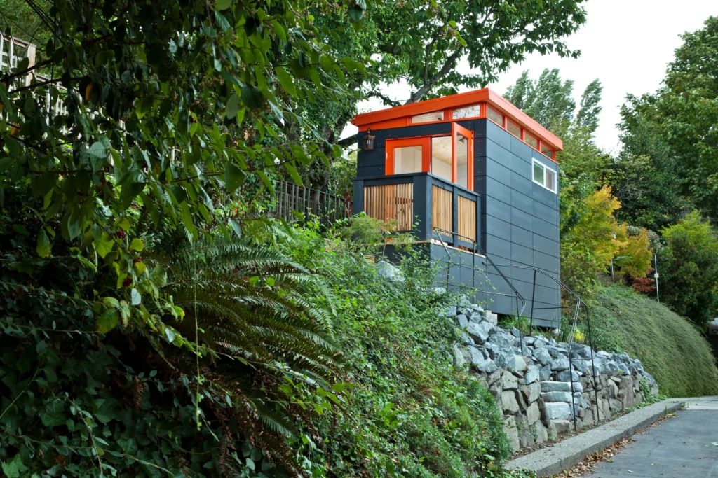 Compact modern shed on hillside with greenery and stairs
