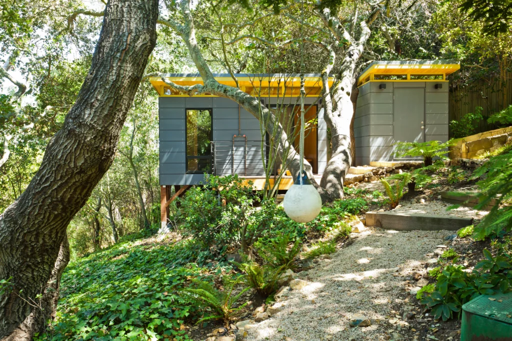 Elevated modern shed with yellow trim on wooded hillside