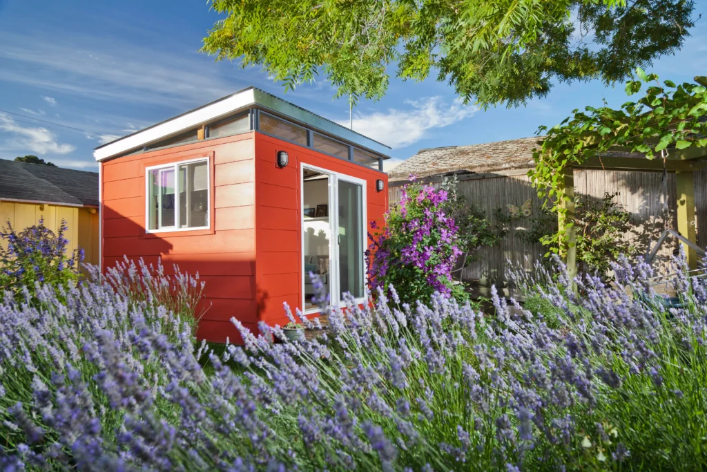 Red prefab shed surrounded by garden and flowers