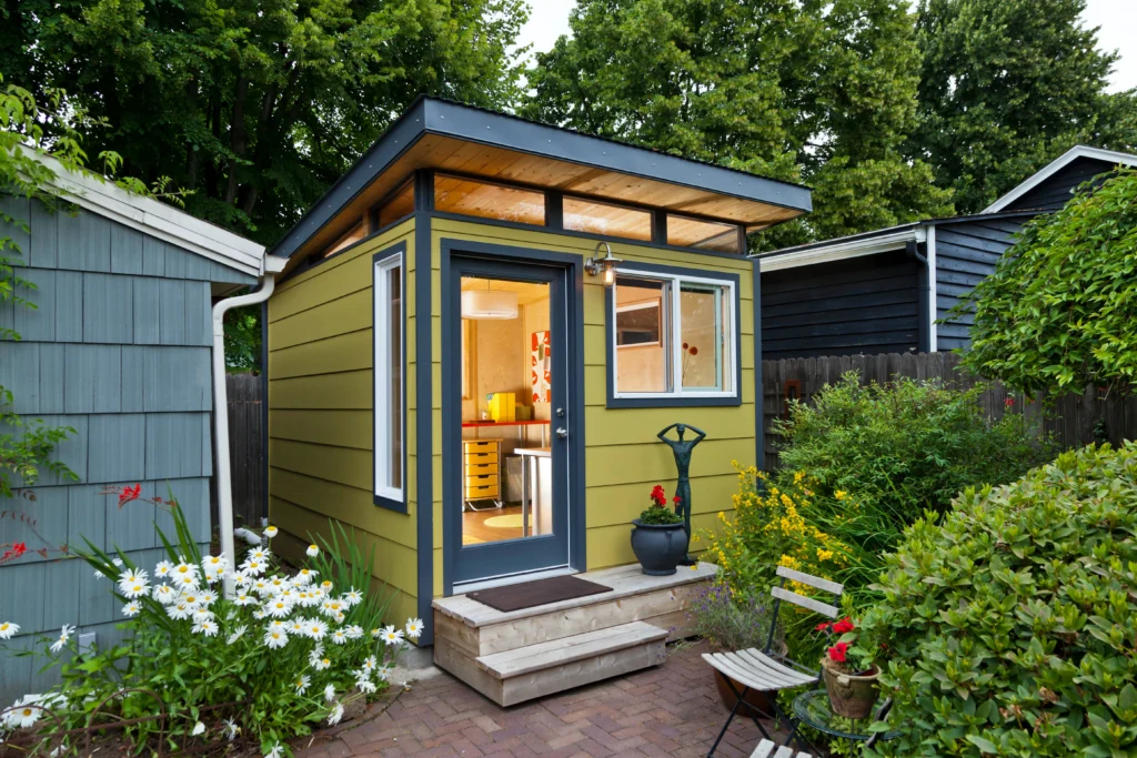 Green backyard shed with garden landscaping and patio
