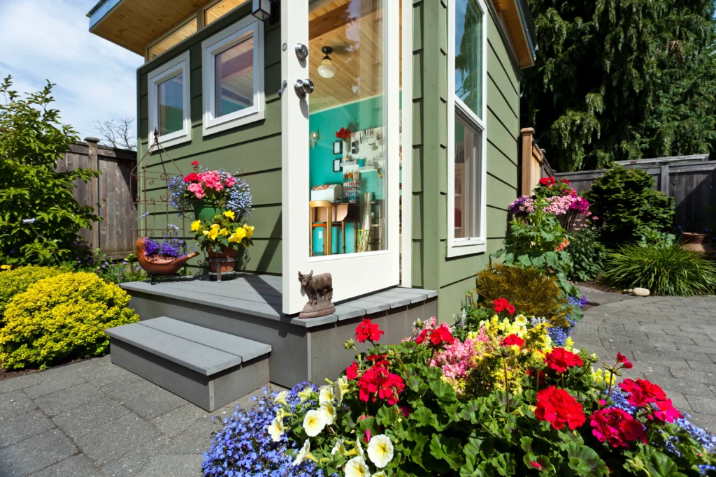 Green backyard shed with colorful flower garden entrance