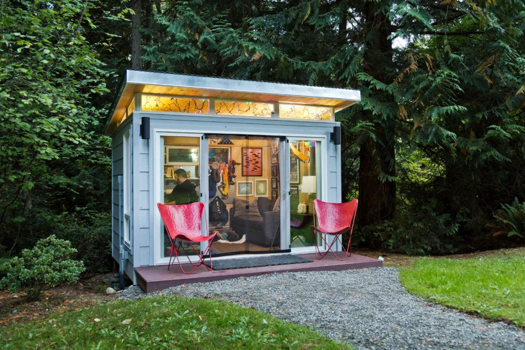 Cozy backyard studio with glass doors and red chairs