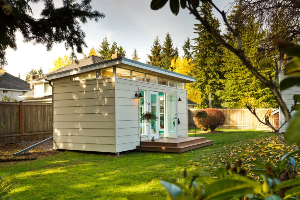 Minimalist backyard studio with sliding glass doors and lawn