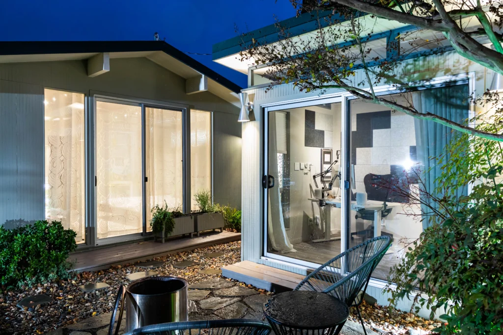 Modern backyard studio with glass walls and evening lighting